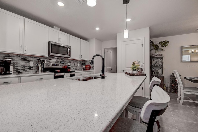 kitchen with appliances with stainless steel finishes, sink, hanging light fixtures, and white cabinets