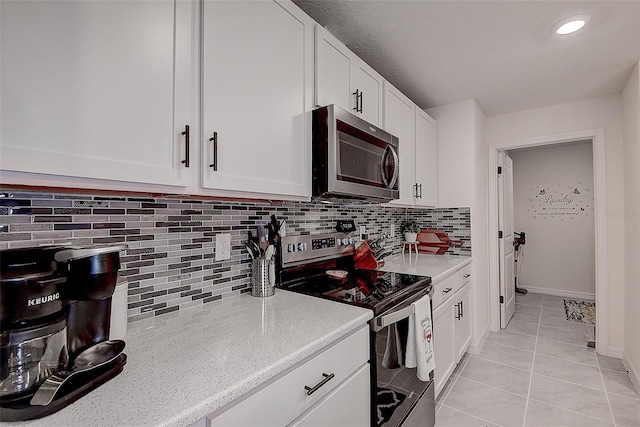 kitchen featuring stainless steel appliances, light tile patterned flooring, white cabinets, and decorative backsplash