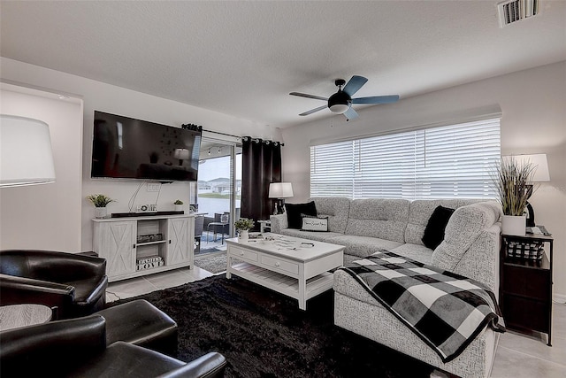 tiled living room with a textured ceiling and ceiling fan