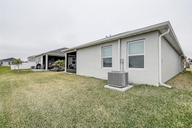 rear view of property featuring a yard and central AC unit