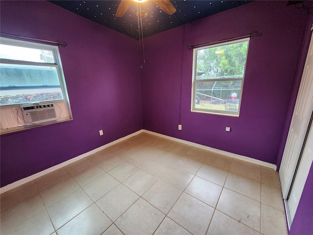 tiled spare room featuring plenty of natural light, cooling unit, and ceiling fan