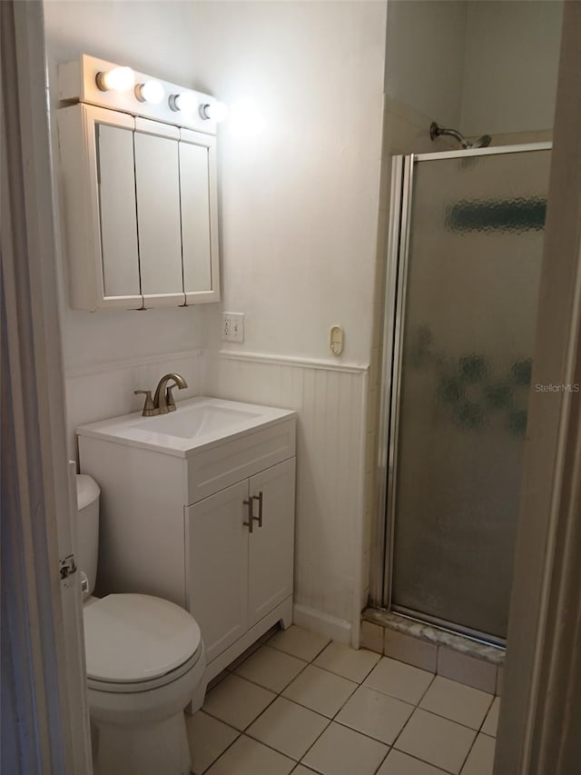 bathroom featuring vanity, toilet, a shower with shower door, and tile patterned flooring