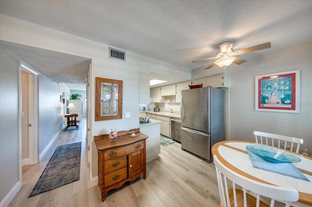 kitchen featuring sink, appliances with stainless steel finishes, white cabinetry, a textured ceiling, and light wood-type flooring