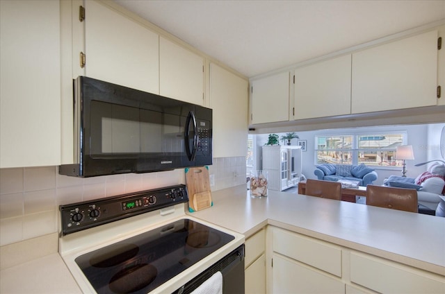 kitchen with electric stove, decorative backsplash, and white cabinets