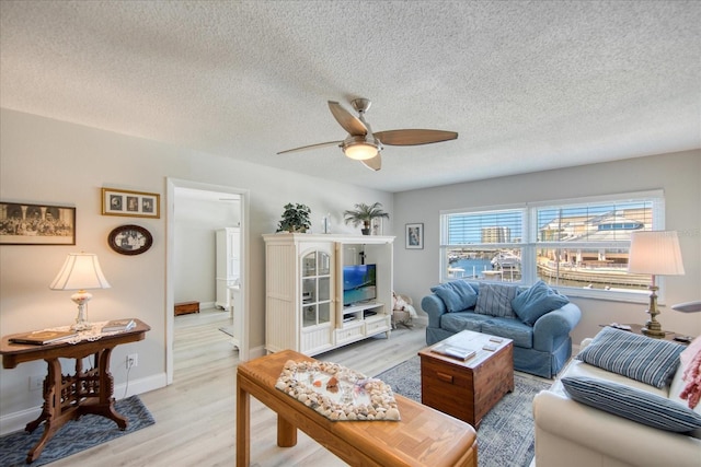 living room with a textured ceiling, light hardwood / wood-style flooring, and ceiling fan