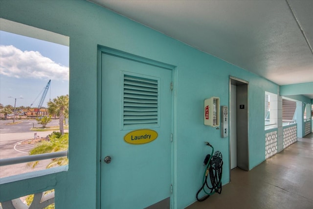 interior space with concrete flooring, elevator, and a textured ceiling