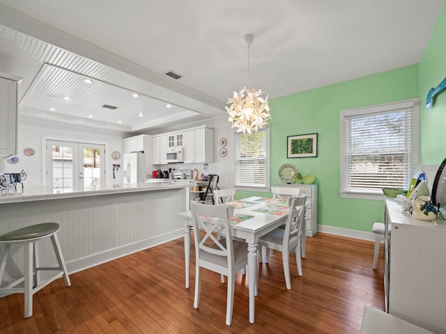 dining room with dark hardwood / wood-style flooring, a notable chandelier, and a raised ceiling