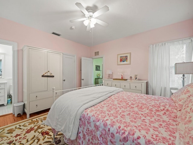 bedroom with wood finished floors, visible vents, and a ceiling fan