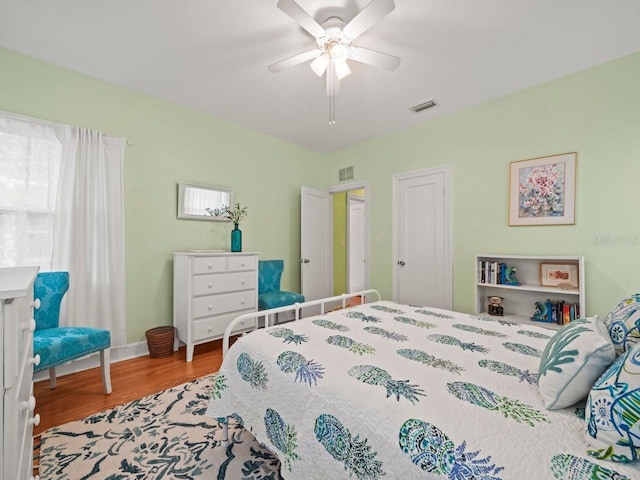bedroom with baseboards, wood finished floors, visible vents, and ceiling fan