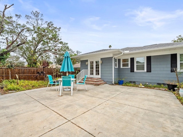 back of property featuring crawl space, french doors, outdoor dining area, fence, and a patio