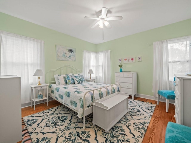 bedroom with light wood finished floors, ceiling fan, and baseboards