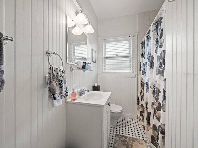 bathroom featuring curtained shower, wooden walls, toilet, tile patterned floors, and vanity
