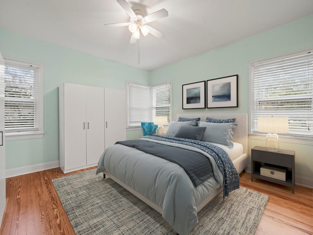 bedroom with light wood-type flooring, a ceiling fan, and baseboards