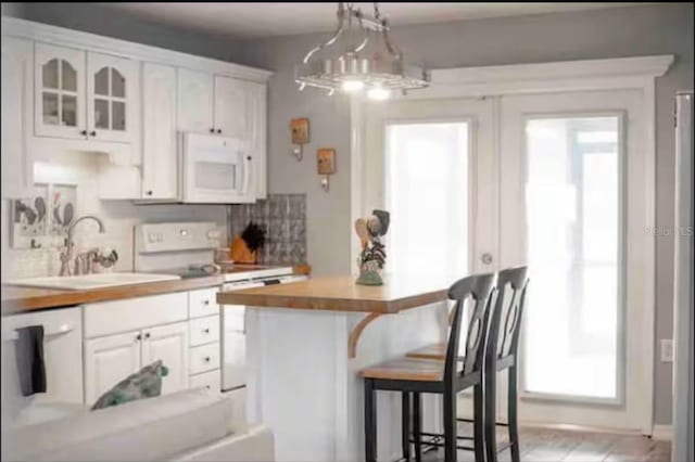 kitchen with white cabinetry, sink, butcher block countertops, and white appliances