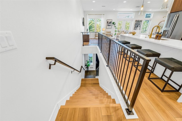 stairs with hardwood / wood-style flooring, sink, and french doors