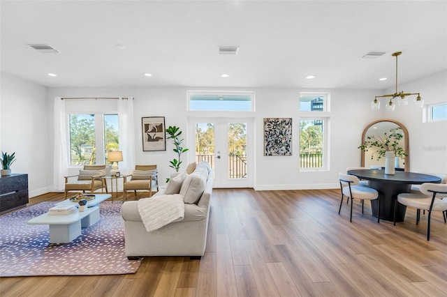 living room with light hardwood / wood-style flooring, french doors, and a chandelier