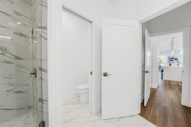 bathroom with wood-type flooring, tiled shower, and toilet