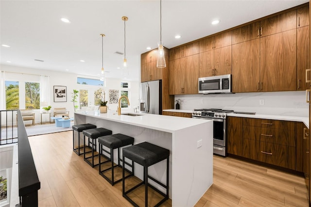 460 87th Ave N, Saint Petersburg, FL 33702 - kitchen featuring light countertops, a kitchen bar, stainless steel appliances, a sink, and light wood-type flooring