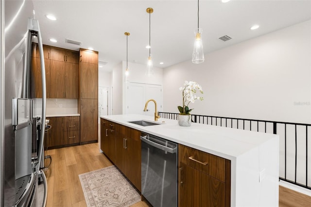 460 87th Ave N, Saint Petersburg, FL 33702 - kitchen with an island with sink, light countertops, a sink, light wood-type flooring, and stainless steel appliances
