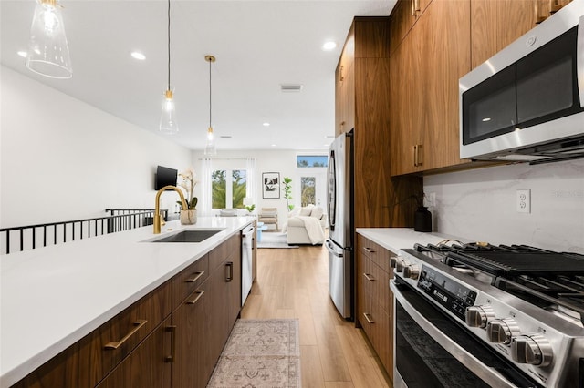 460 87th Ave N, Saint Petersburg, FL 33702 - kitchen featuring decorative backsplash, light countertops, light wood finished floors, appliances with stainless steel finishes, and a sink