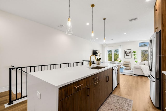 460 87th Ave N, Saint Petersburg, FL 33702 - kitchen with a sink, a center island with sink, light wood-style flooring, stainless steel appliances, and visible vents