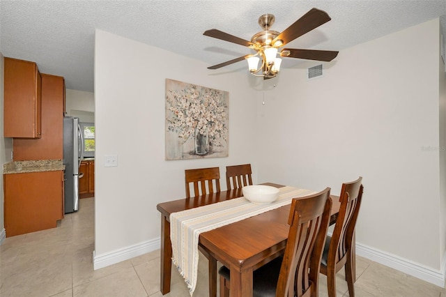 dining room featuring ceiling fan, a textured ceiling, and light tile patterned flooring