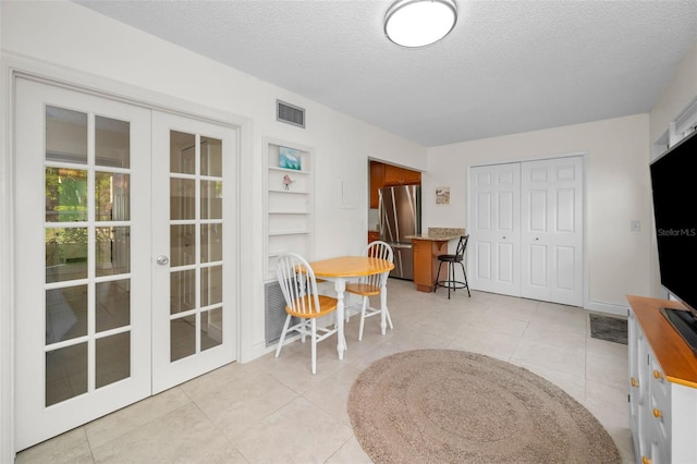 tiled dining area with french doors and a textured ceiling