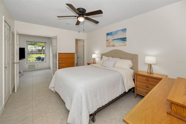 tiled bedroom with ceiling fan and a textured ceiling