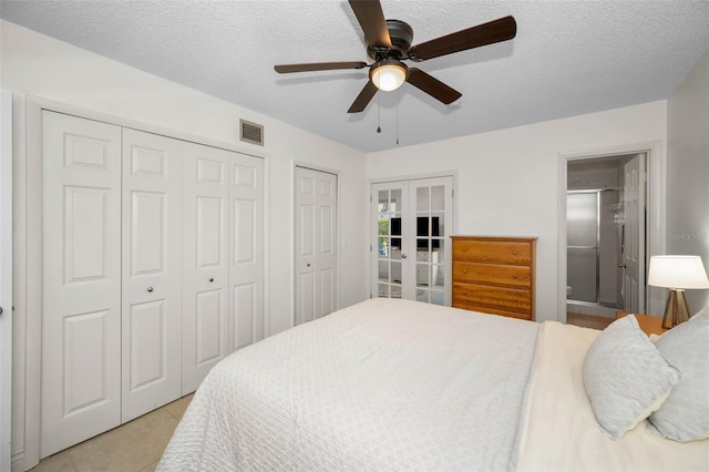 bedroom with a textured ceiling, french doors, multiple closets, and light tile patterned flooring