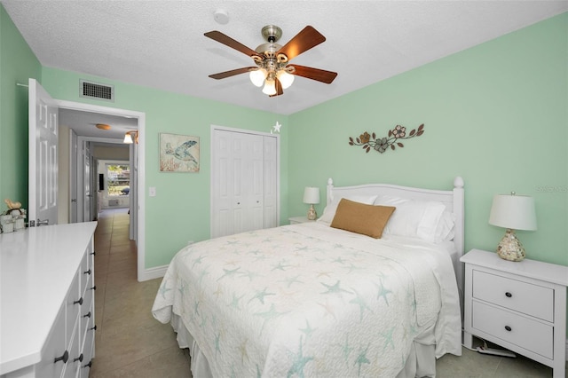 tiled bedroom featuring ceiling fan, a closet, and a textured ceiling