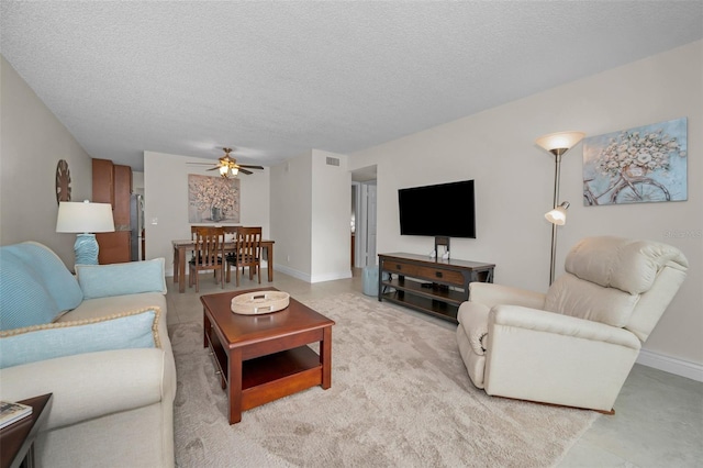 living room with ceiling fan and a textured ceiling