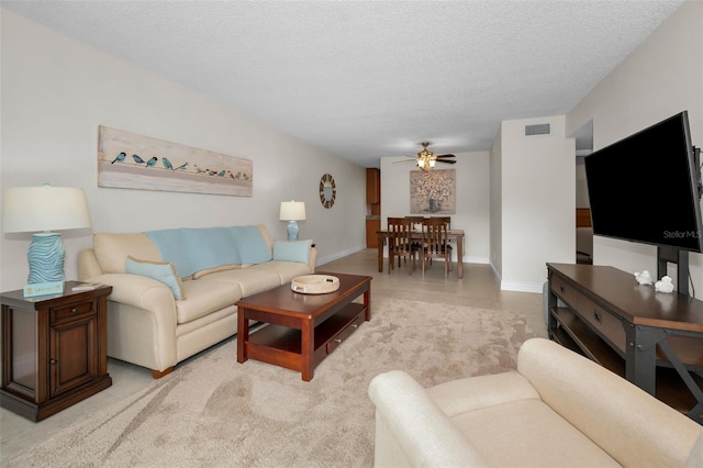 living room with ceiling fan and a textured ceiling