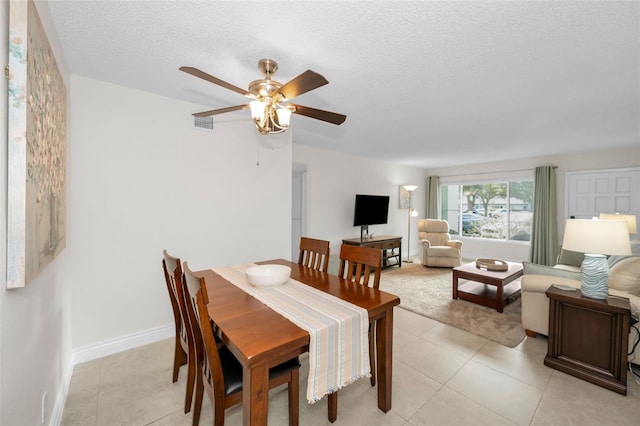 tiled dining room with ceiling fan and a textured ceiling