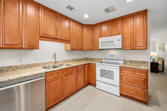 kitchen featuring light stone counters, white appliances, sink, and light tile patterned floors