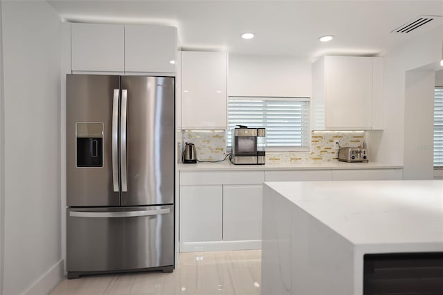 kitchen featuring white cabinetry, stainless steel fridge, and backsplash