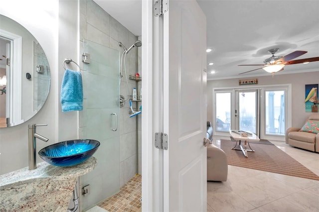 bathroom with walk in shower, ceiling fan, crown molding, and sink