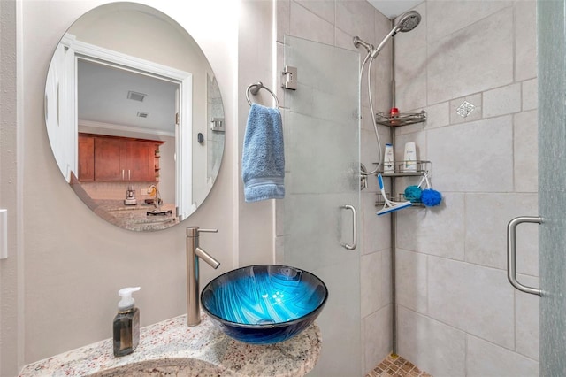 bathroom featuring a shower with door, crown molding, and sink