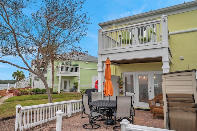 rear view of property featuring a balcony, a yard, and a patio