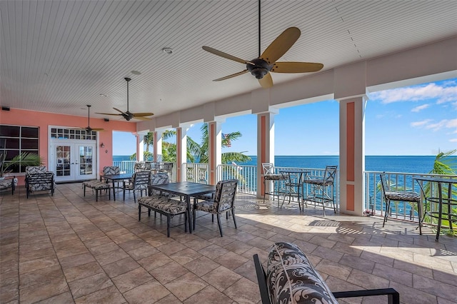 view of patio with a water view, ceiling fan, exterior bar, and french doors