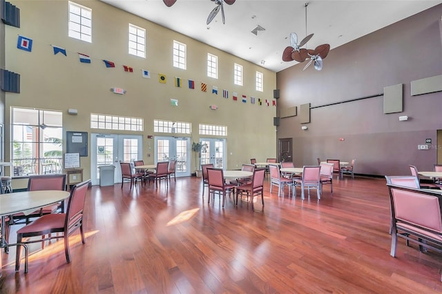 dining room featuring french doors, ceiling fan, wood-type flooring, and a high ceiling