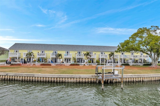 rear view of house with a water view and a lawn