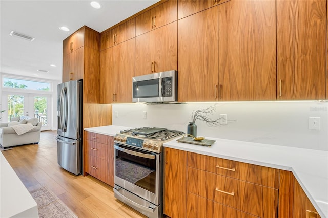 kitchen with french doors, appliances with stainless steel finishes, tasteful backsplash, and light wood-type flooring