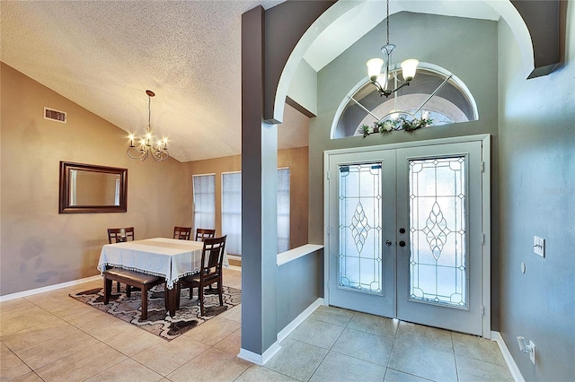 entrance foyer featuring light tile patterned floors, high vaulted ceiling, a textured ceiling, french doors, and a chandelier