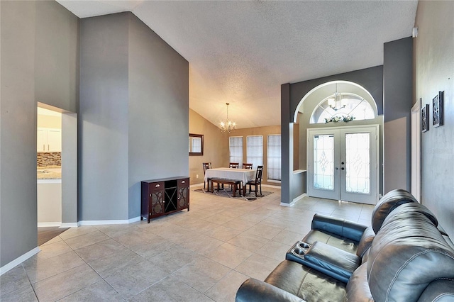 foyer featuring high vaulted ceiling, light tile patterned floors, a chandelier, and french doors