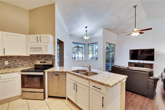 kitchen with sink, appliances with stainless steel finishes, decorative backsplash, decorative light fixtures, and vaulted ceiling