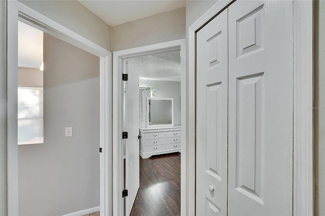 corridor with dark hardwood / wood-style flooring and a textured ceiling