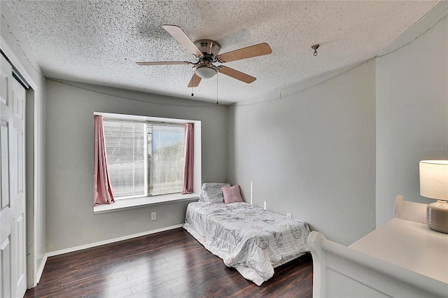 bedroom featuring dark wood-type flooring, ceiling fan, a closet, and a textured ceiling