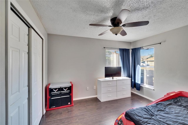 bedroom with dark wood-type flooring, ceiling fan, a closet, and a textured ceiling