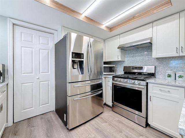 kitchen with white cabinetry, stainless steel appliances, and wall chimney range hood