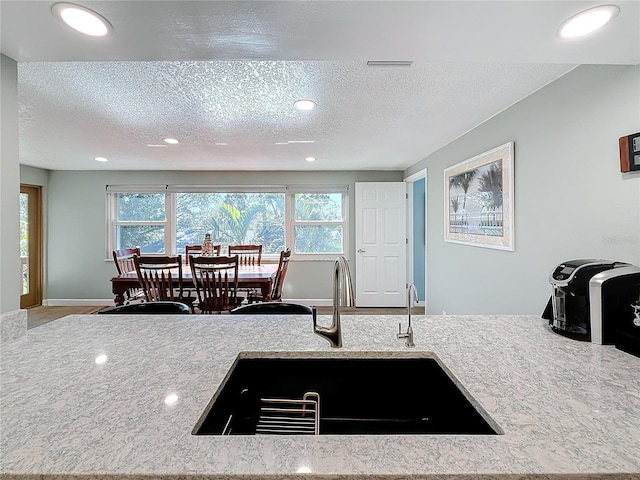 kitchen featuring sink, a wealth of natural light, and light stone countertops